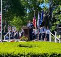 a man stands at a podium in Gale Park with service flags and the statue in the background