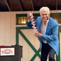 Man in a blue suit jacket performing card tricks