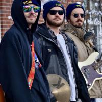 3 guys posing for the camera holding instruments