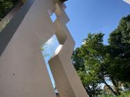 A low angle shot looking up through the openings in the sculpture columns at the blue sky