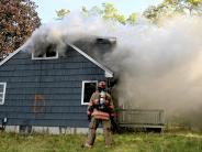 a fire fighter stands in front of a smoky house