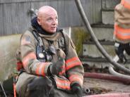 a fire fighter kneeling outside a burning home