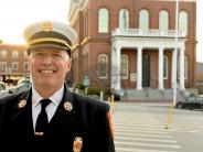 New Fire Chief Justin Pizon stands on Water Street with the Exeter Town Hall in the background