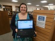 Picture of Librarian holding an open laptop facing the camera.