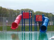 A red slide and a shorter blue slide stand side by side over the pool 
