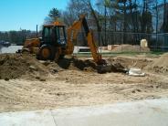 A crane digs the earth in the future spray pad site 