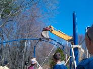 Another angle of the roof beam being raised via crane 