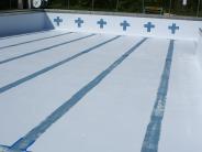 The pool sits empty, its blue striped lanes clearly worn from time 