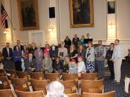 A group of people hold up their awards in the NH state house
