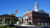 A photo of downtown with the Band Stand on the left and old Exeter Town Hall on the right under a blue sky