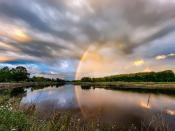 A photo of a rainbow coming out of the Squamscott River as seen from Swasey Parkway