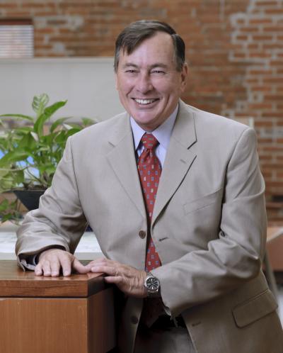 Photo of John Merkle in a tan suit with red tie