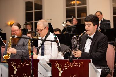 A group of people playing instruments such as saxophones, trumpets, trombones and drums