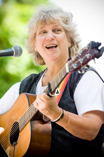 Woman strumming a guitar and singing