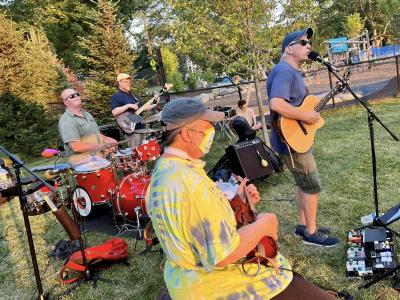 A band performing outside with guitars drums and keyboards