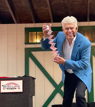 Man in a blue suit jacket performing card tricks
