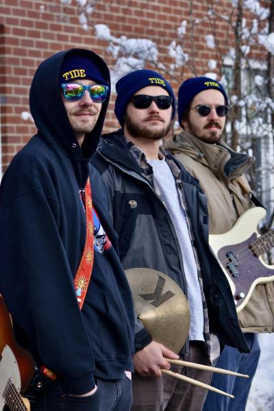 3 guys posing for the camera holding instruments